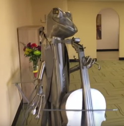 Photograph of a metal frog playing a cello at The Changing Place.