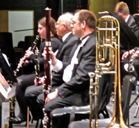Photograph of 3 woodwind players and a trombone on a stand